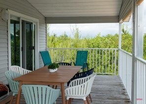 Enjoy al fresco dining in this serene outdoor space with a table and chairs, surrounded by lush greenery.