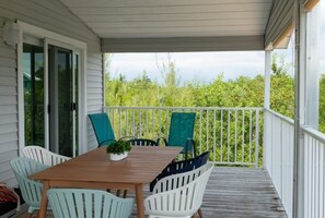 Enjoy al fresco dining in this serene outdoor space with a table and chairs, surrounded by lush greenery.