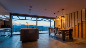 A modern kitchen with a large island, a dining area with a table and chairs, and a view of the cityscape through large windows. - Villa Eva w/ Pool & Spa in Goriška Brda, Dobrovo v Brdih, Slovenia (Dobrovo v Brdih)
