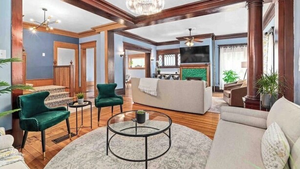 A spacious living room with a chandelier, a sofa, a coffee table, and a television.