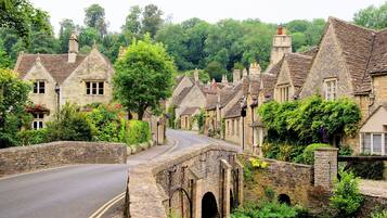 A stone bridge over a river, surrounded by traditional stone houses with pitched roofs and ivy.