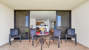 Een balkon met een tafel en vier stoelen, een keuken op de achtergrond en een schuifpui.
