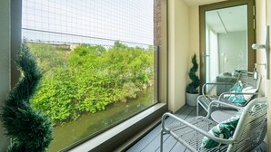 Een balkon met rieten stoelen en uitzicht op een rivier en groen.