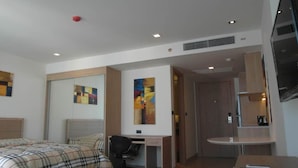 A hotel room with two beds, a desk, a chair, a small table, and a TV. - The Cliff Condominium Floor 10th Number 1007 (Pattaya)