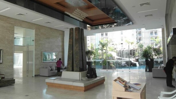 A spacious lobby with a modern design, featuring a seating area, a reception desk, and a view of an outdoor pool area. - The Cliff Condominium Floor 10th Number 1007 (Pattaya)