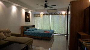 Quarto moderno com cama, sofá, televisão e ventoinha no teto.