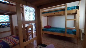 Una habitación con literas, una silla de madera y un ventanal con vidrio decorado.