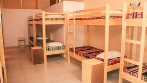 Un dormitorio con literas, un escritorio pequeño y un refrigerador.