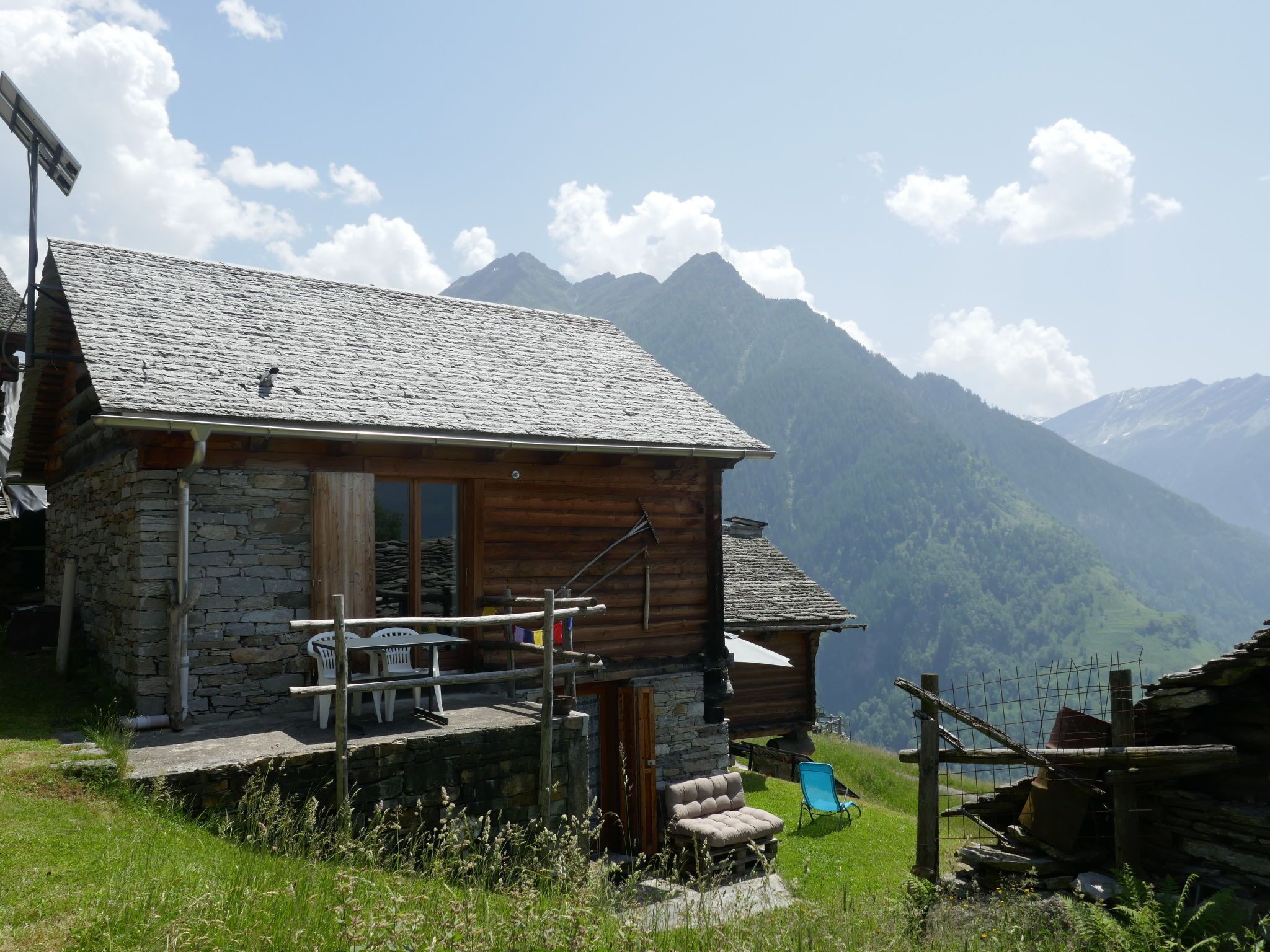 Ein rustikales Berglodge mit Stein- und Holzbauweise, einer Holzveranda und Blick auf die umliegenden Berge.