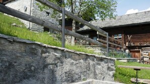 Un bâtiment rustique en pierre, avec une clôture en bois et une structure en bois sur le toit.