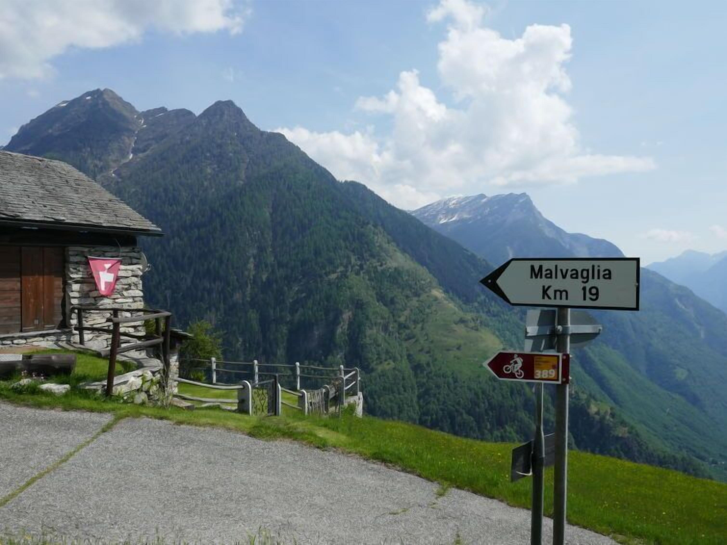 Uma cabana de montanha com uma placa indicando que Malvaglia fica a 19 km de distância.