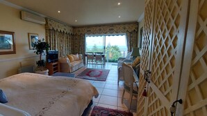 Hotelkamer met een groot bed, een televisie, een zithoek met stoelen en uitzicht op de omgeving.