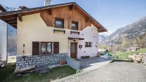 A two-story house with a stone foundation, wooden upper structure, and a stone-paved entrance.
