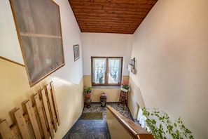 A narrow hallway with a wooden ceiling, a window with curtains, a wooden bench, and potted plants. - Apartment "La Mansarda di Chiara e Silvio" close to Skiing Area with Mountain View (Trasquera)