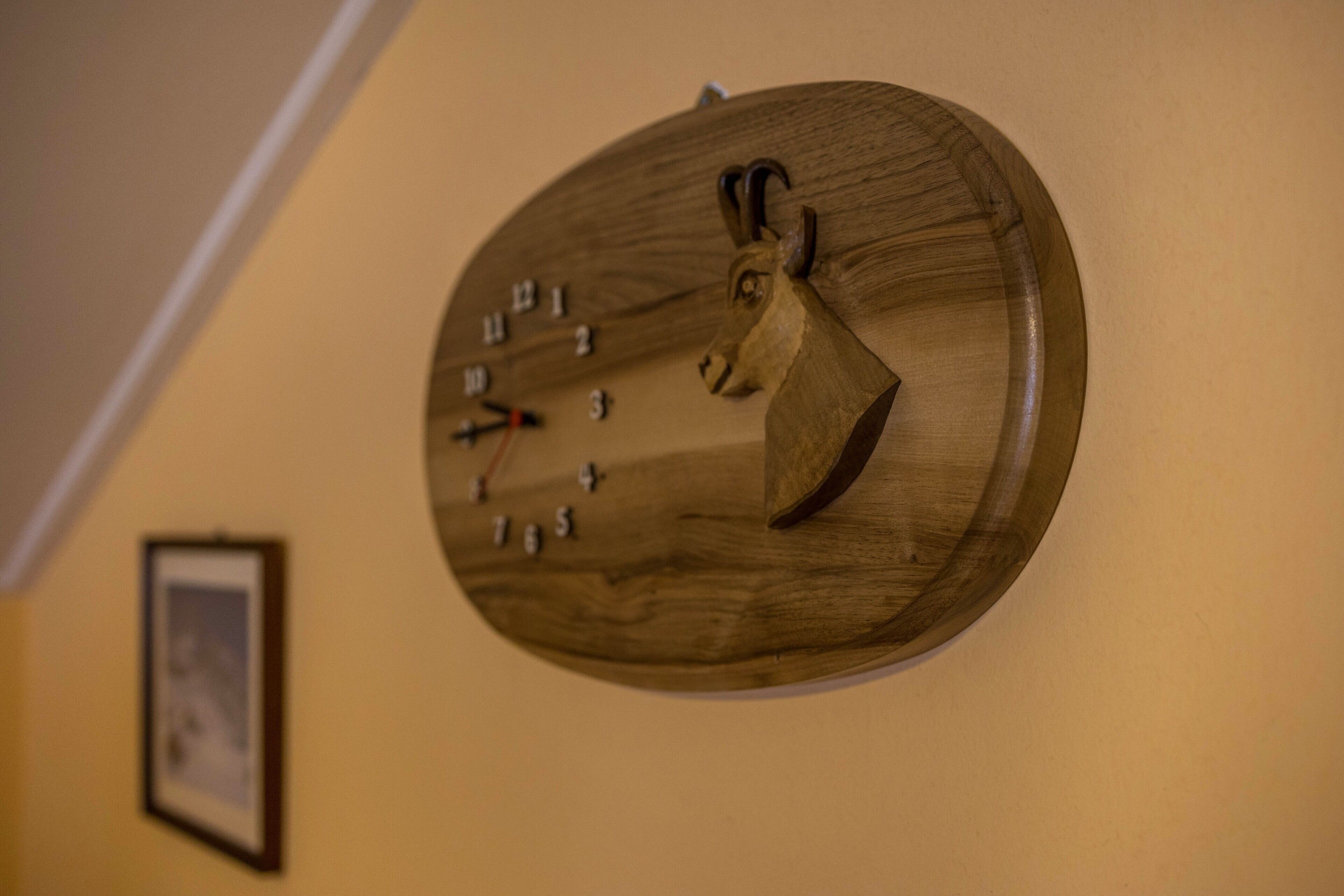 Une horloge murale en bois au design original, fixée sur un mur sobre.