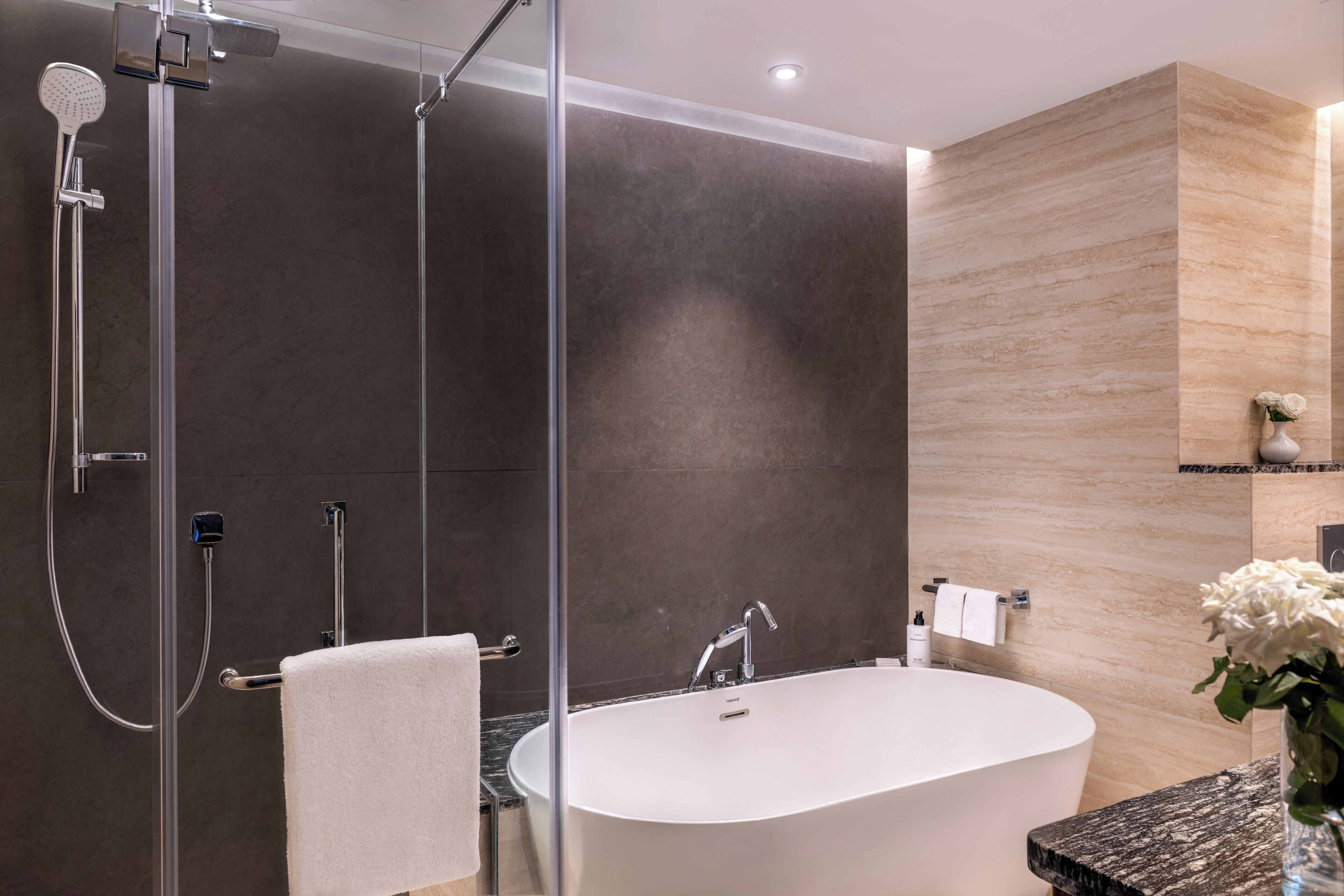 A modern bathroom with a freestanding bathtub, a glass-enclosed shower, and a marble countertop.