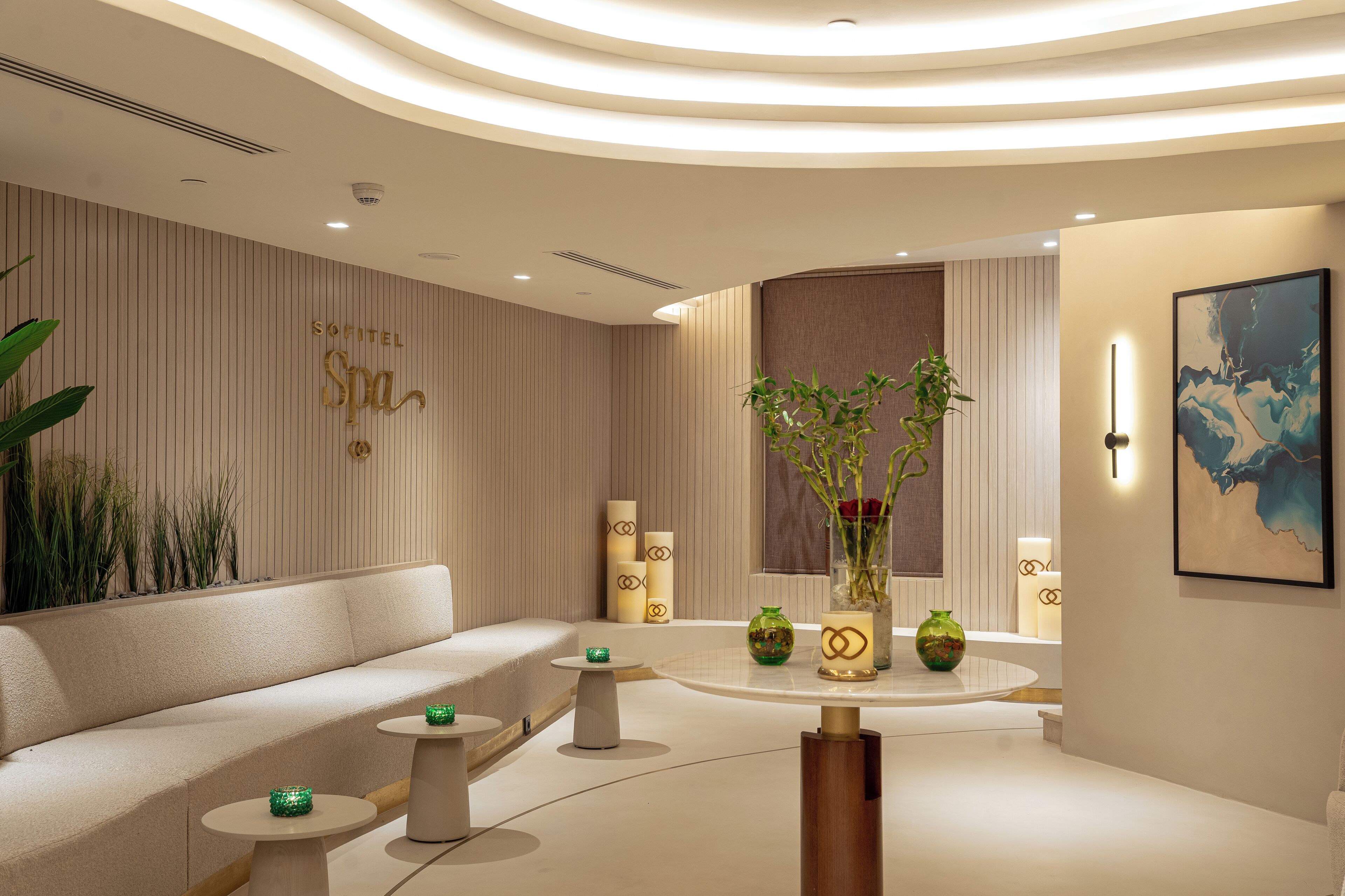 A modern spa interior with a sofa, small tables, and decorative vases.