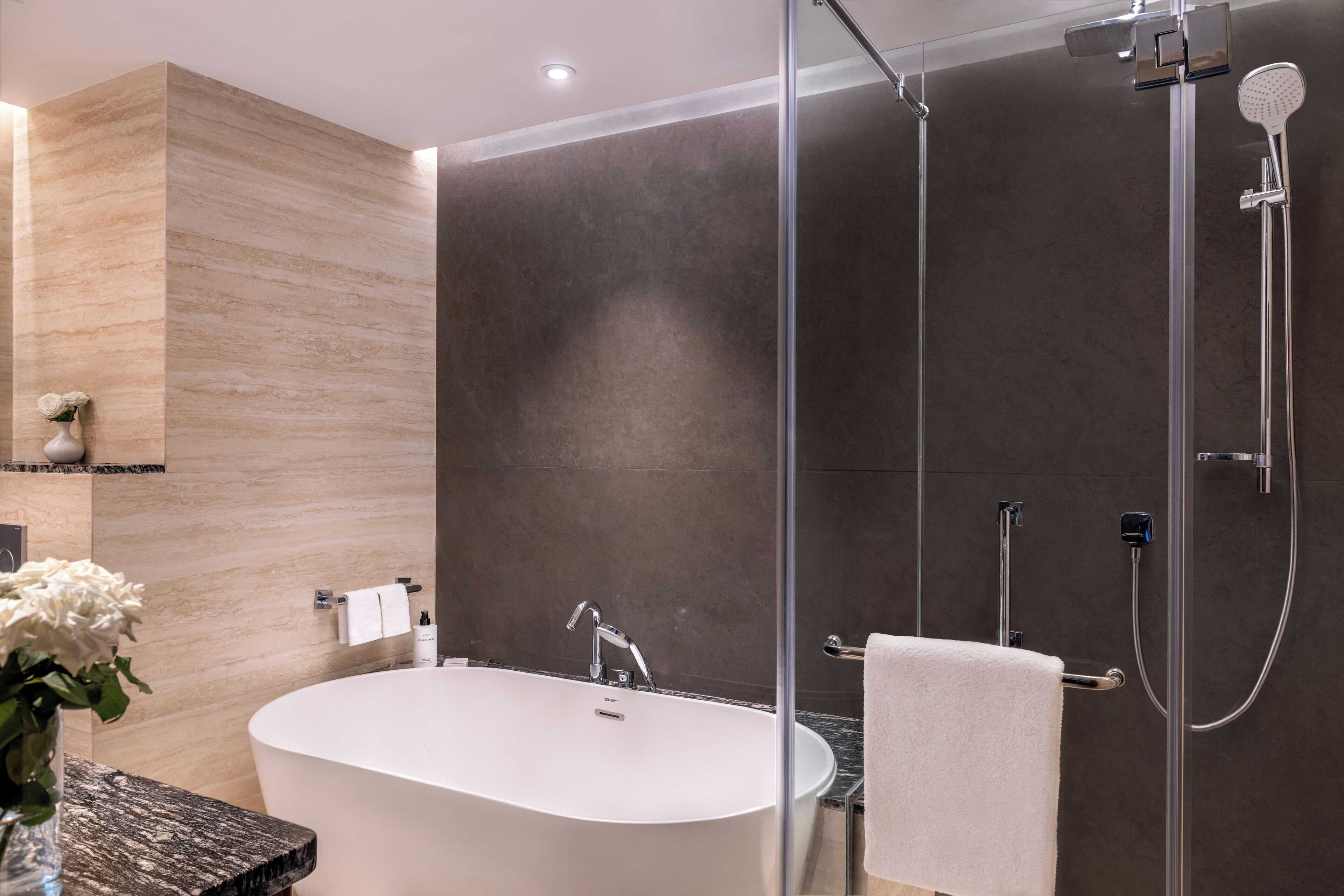 A modern bathroom with a freestanding bathtub, a glass shower enclosure, and a marble countertop.