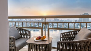 A balcony with wicker furniture, a table with fruit, and a city view.