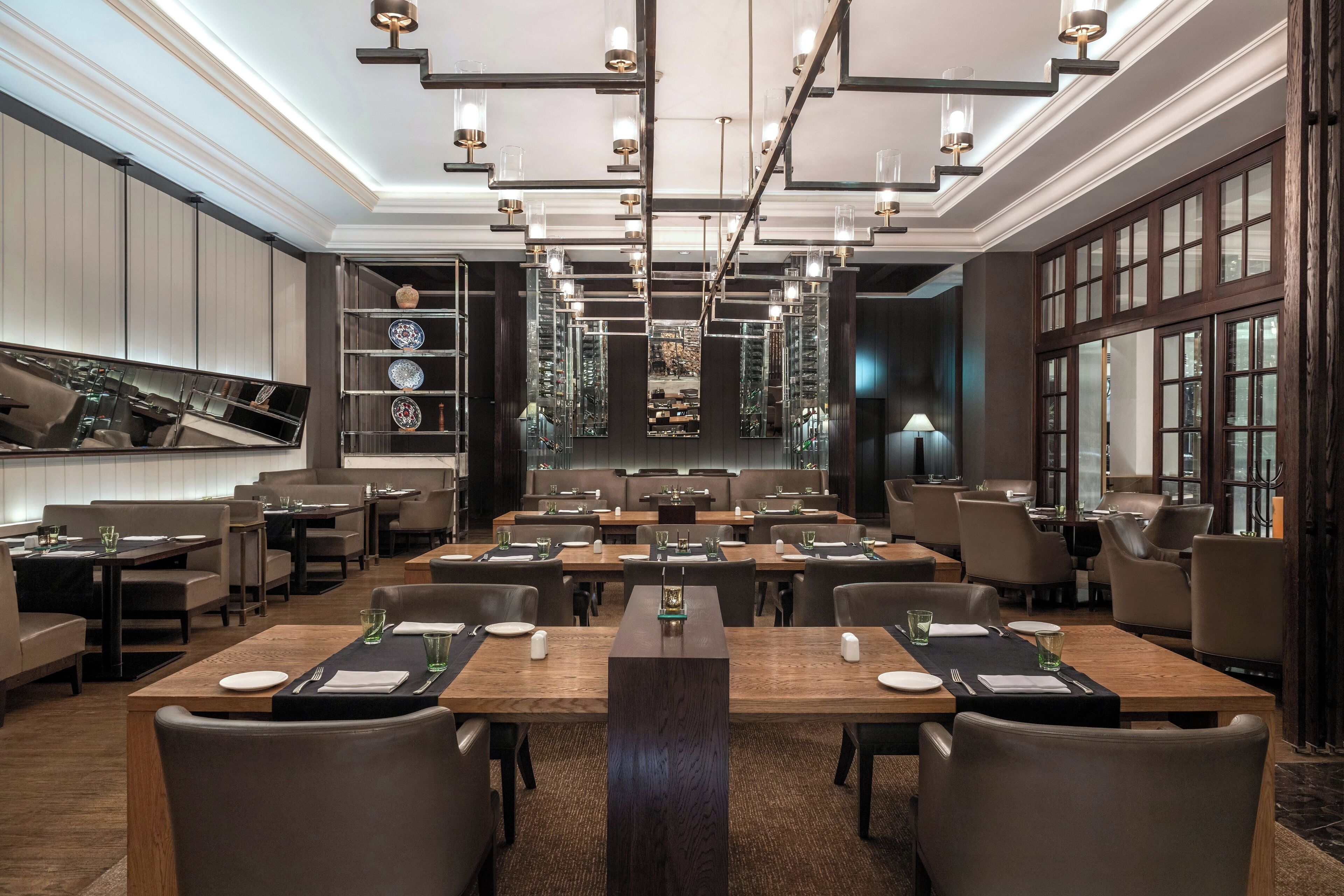 A modern restaurant with a long dining area, multiple tables, and a central walkway.