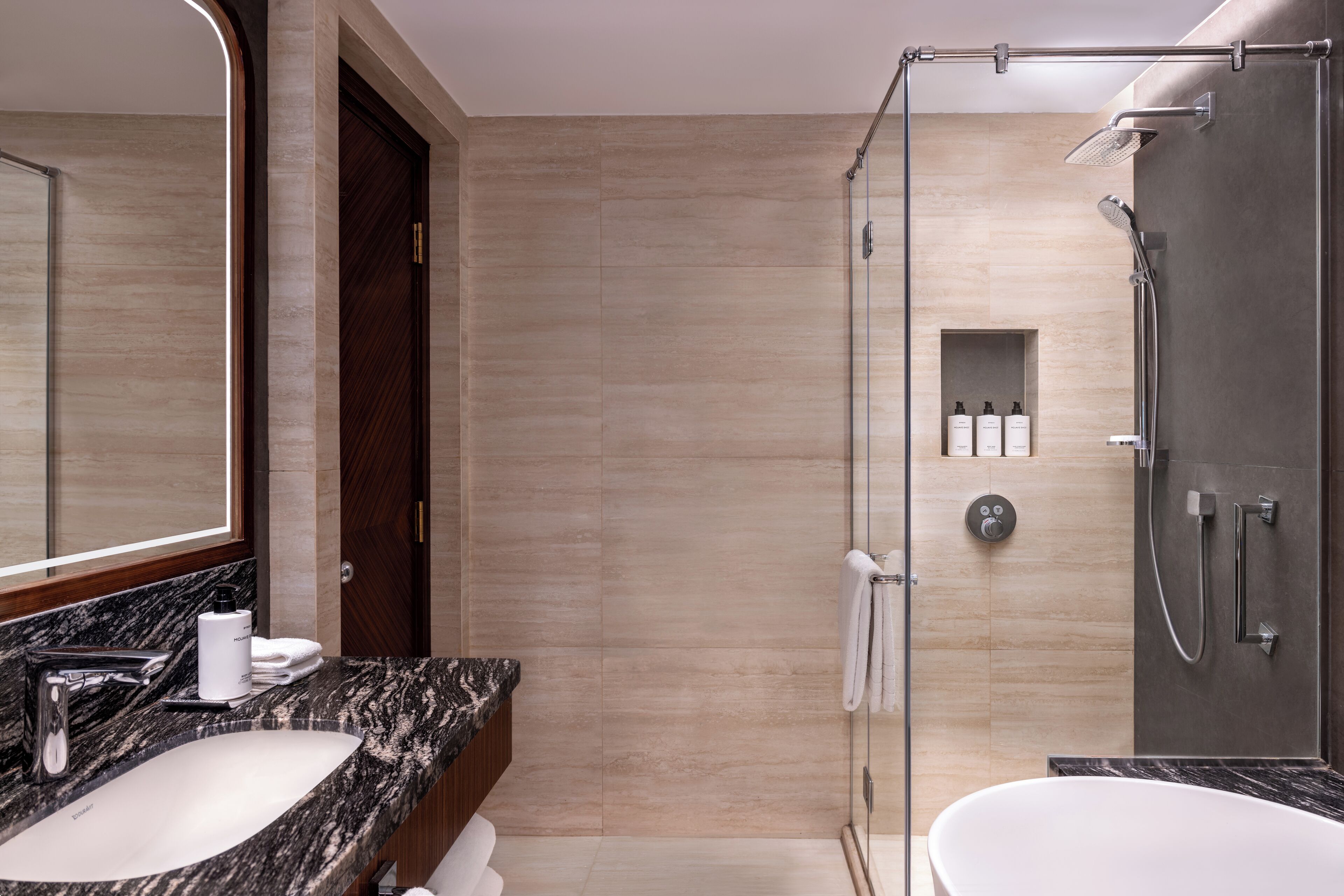 Ein modernes Badezimmer mit Marmorwaschbecken, einem großen Spiegel, einer Duschkabine und einer Badewanne.