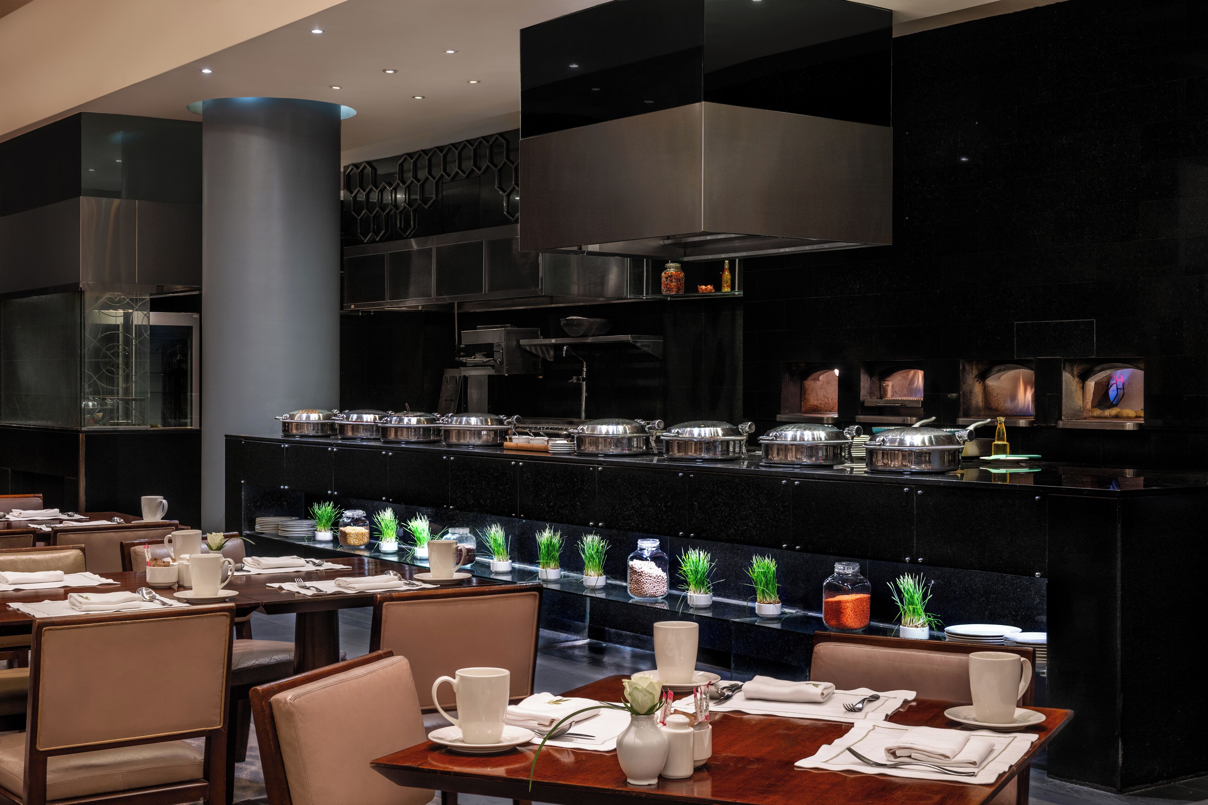 Een modern restaurant met een lange toonbank, verschillende zithoeken en diverse gerechten op de toonbank.