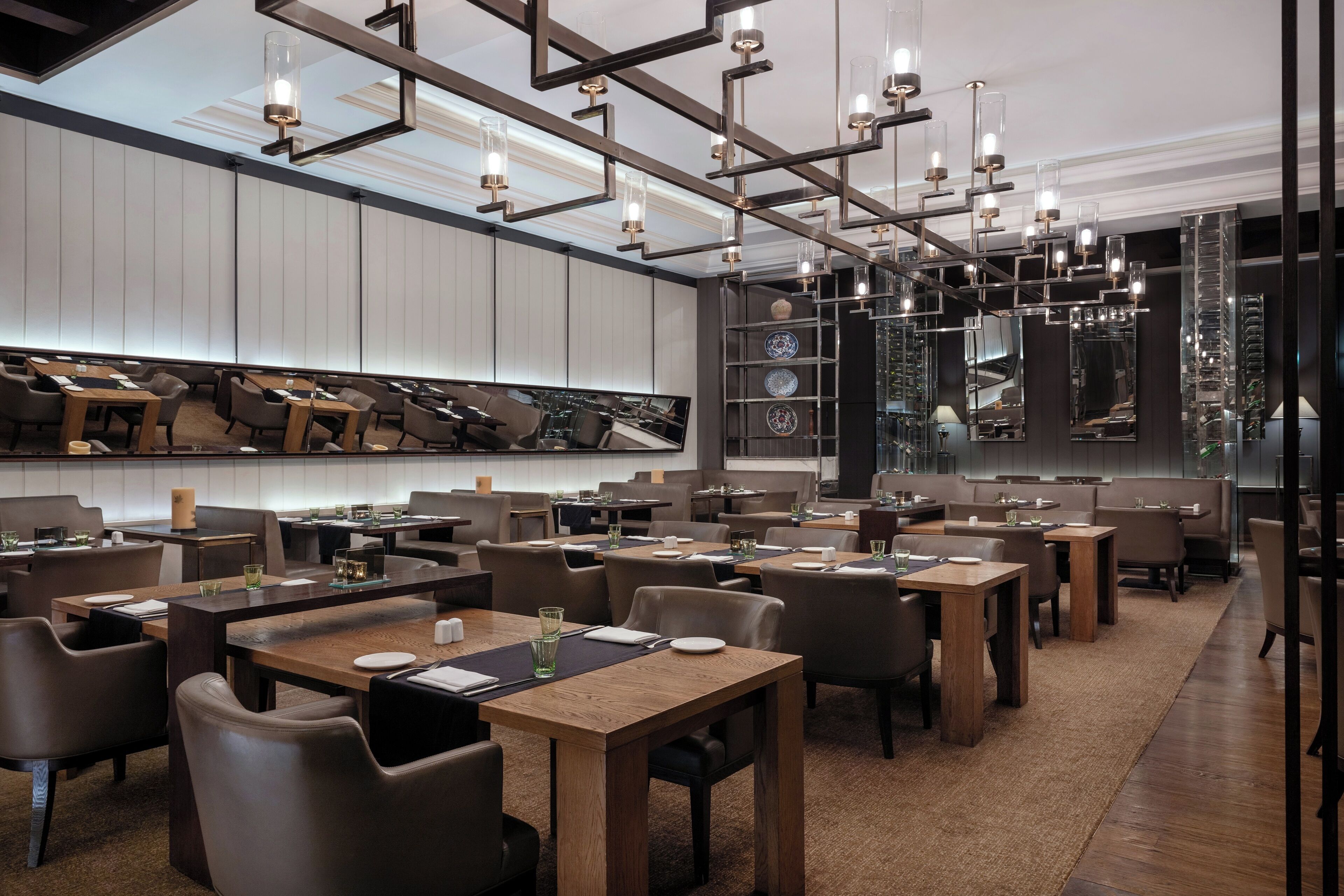 A modern restaurant with wooden tables and chairs, a high ceiling with exposed beams, and a large wall-mounted display of decorative items.