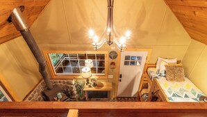 A cozy cabin interior with a stone fireplace, wooden ceiling, and a chandelier. - Storybook Cabin on Sahara Creek - 8mi to MRNP! (Ashford)