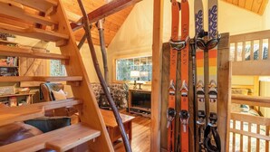 A wooden staircase leading to a lofted area with a ski rack, wooden furniture, and a stone wall. - Storybook Cabin on Sahara Creek - 8mi to MRNP! (Ashford)