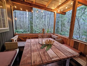 Un pontile in legno con tavolo e panche, circondato da una vista sulla foresta.