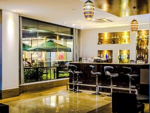 Enjoy a drink at the bar, surrounded by a view of the outdoor seating area.