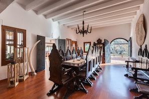 Una habitación con una larga mesa de madera, una araña y un amplio ventanal con vistas.