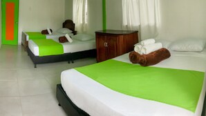 A hotel room with two beds, each with green and white bedding, a wooden nightstand, and a green door. - Room-room With 1 Double bed and 2 Single (Pereira)