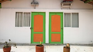 A building with two green doors, a small balcony with a toy car, and potted plants in front. - Room-room With 1 Double bed and 2 Single (Pereira)