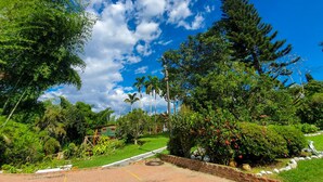 A lush garden with a variety of trees and shrubs, a paved pathway, and a small brick structure. - Room-tree House Finca La Floresta Verde (Pereira)