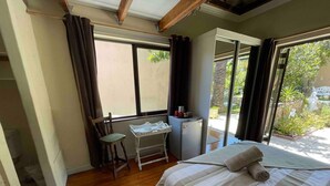 Een slaapkamer met een bed, een stoel, een klein tafeltje en een koelkast.