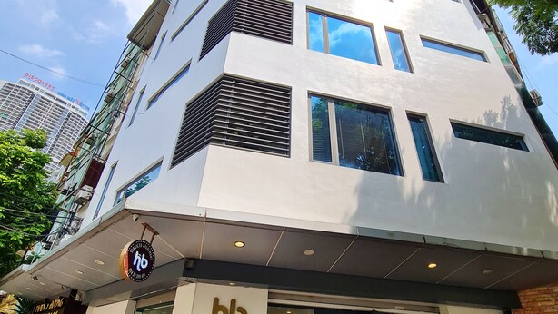Um prédio de apartamentos com serviços, design moderno, com vários andares, grandes janelas e uma placa indicando ser um apartamento com serviços.
