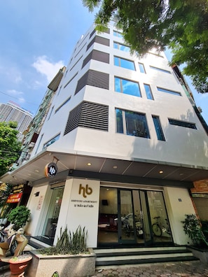 Un edificio de apartamentos con servicios de diseño moderno, con varios pisos, grandes ventanales y un letrero que indica que se trata de un apartamento con servicios.