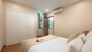 Quarto com cama, guarda-roupa e janela com vista para o verde.