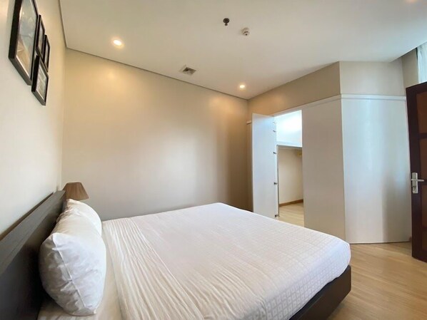 Un dormitorio con una cama grande, una lámpara de noche y un armario.