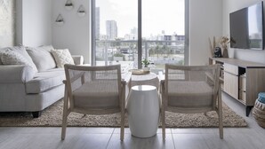 A modern living room with a sofa, two wicker chairs, a coffee table, and a TV. - Artistic Design District Stay, Parking, Pool, Gym (Miami)