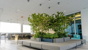 A modern indoor seating area with a sofa and chairs, a small table, and a large window. - Artistic Design District Stay, Parking, Pool, Gym (Miami)
