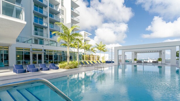 A modern hotel with a pool area, lounge chairs, and a view of the ocean. - Artistic Design District Stay, Parking, Pool, Gym (Miami)