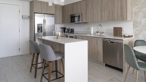 A modern kitchen with a central island, bar stools, and a dishwasher. - Artistic Design District Stay, Parking, Pool, Gym (Miami)