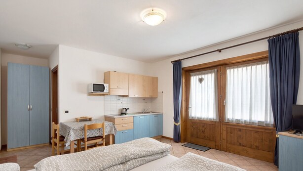 Ein Zimmer mit Bett, Schreibtisch, Mikrowelle und Fernseher.