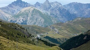 Eine gebirgige Landschaft mit einer kurvigen Straße, Gebäuden und einer Brücke.