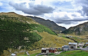 A mountainous landscape with a small settlement featuring wooden buildings and a road.