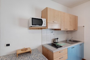 Une cuisine équipée d’un four à micro-ondes, d’un évier, de meubles en bois et d’un crédence carrelée.