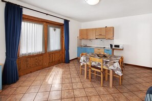 A kitchen with wooden cabinets, a microwave, and a dining table with chairs.