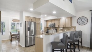 Una cocina moderna con electrodomésticos de acero inoxidable, un microondas y un reloj en la pared.